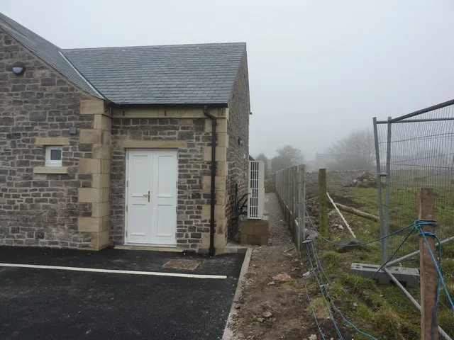 A compact heat pump against the wall of a stone-built house — in a conservation area, a position away from the street usually avoids a planning application.