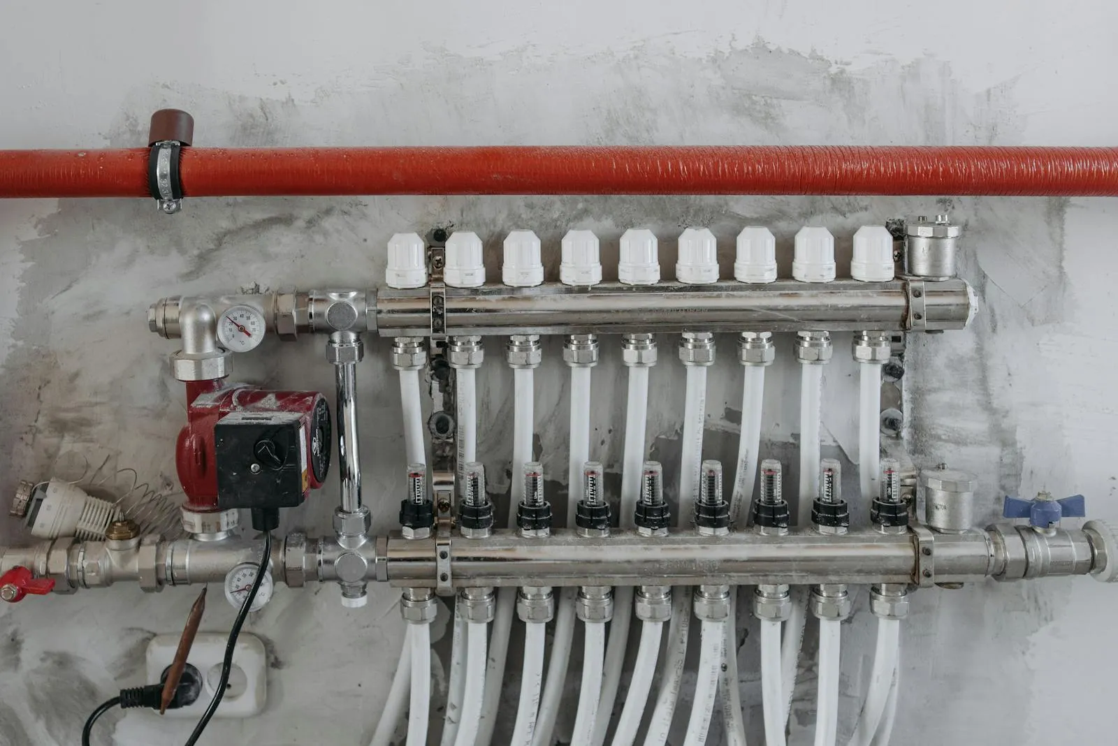 An underfloor heating manifold with flow valves — every heat pump design, radiators or underfloor, starts from a room-by-room heat loss calculation.