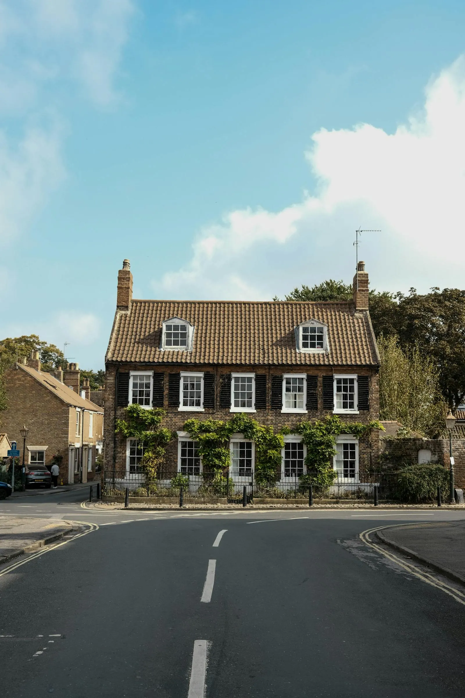A handsome brick UK townhouse with sash windows and a tile roof on a quiet street corner — period housing stock representative of the kind found along the Riverside area of Cambridge.